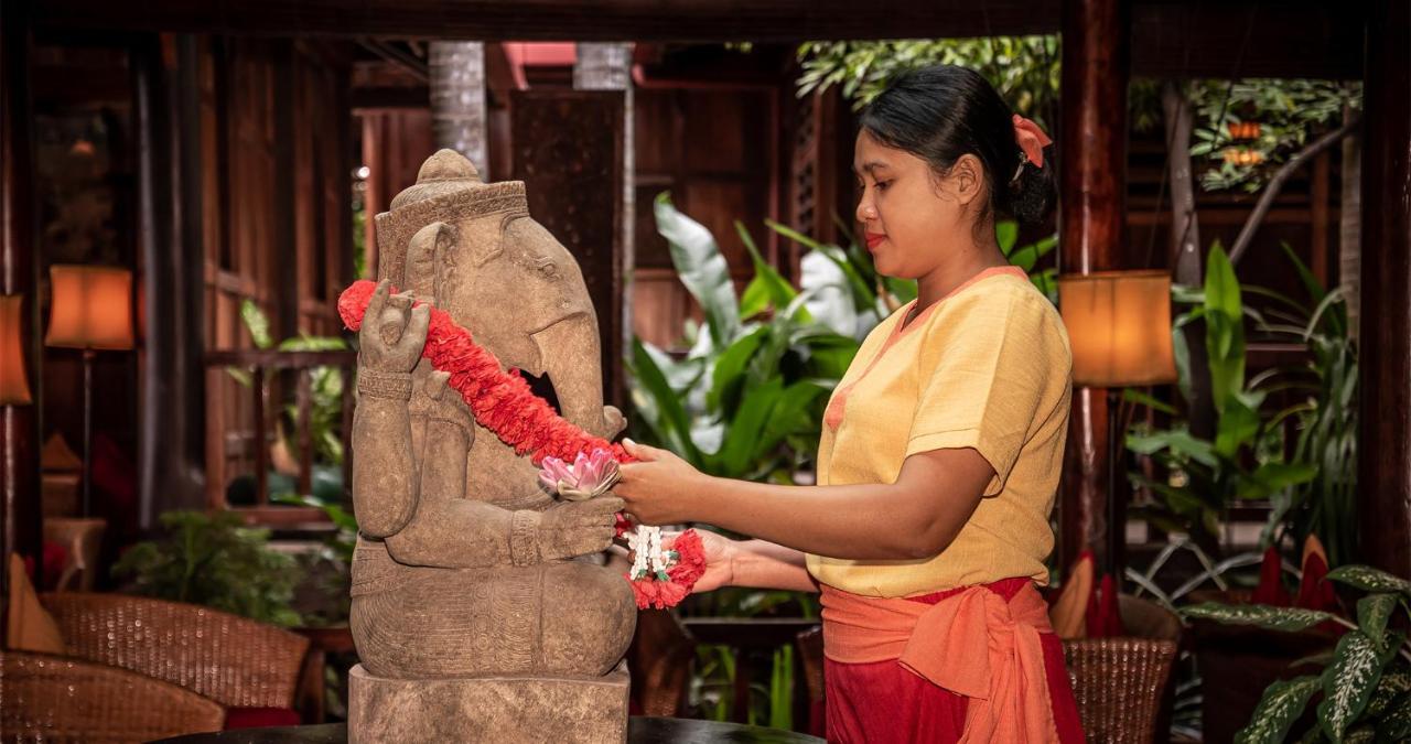Angkor Village Hotel - Small Luxury Hotels Of The World Сіємреап Екстер'єр фото A woman in Thailand, wearing traditional Thai clothing, garlands a statue of the Hindu god Ganesha.